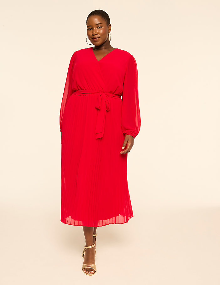 A woman in a red dress stands against a plain, light background.