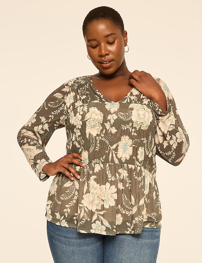 A woman in a floral peplum top stands against a plain, light-colored background.