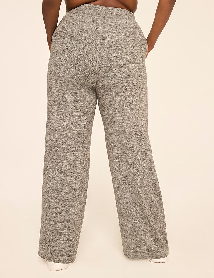 A person wearing gray sweatpants stands against a plain, light-colored background.