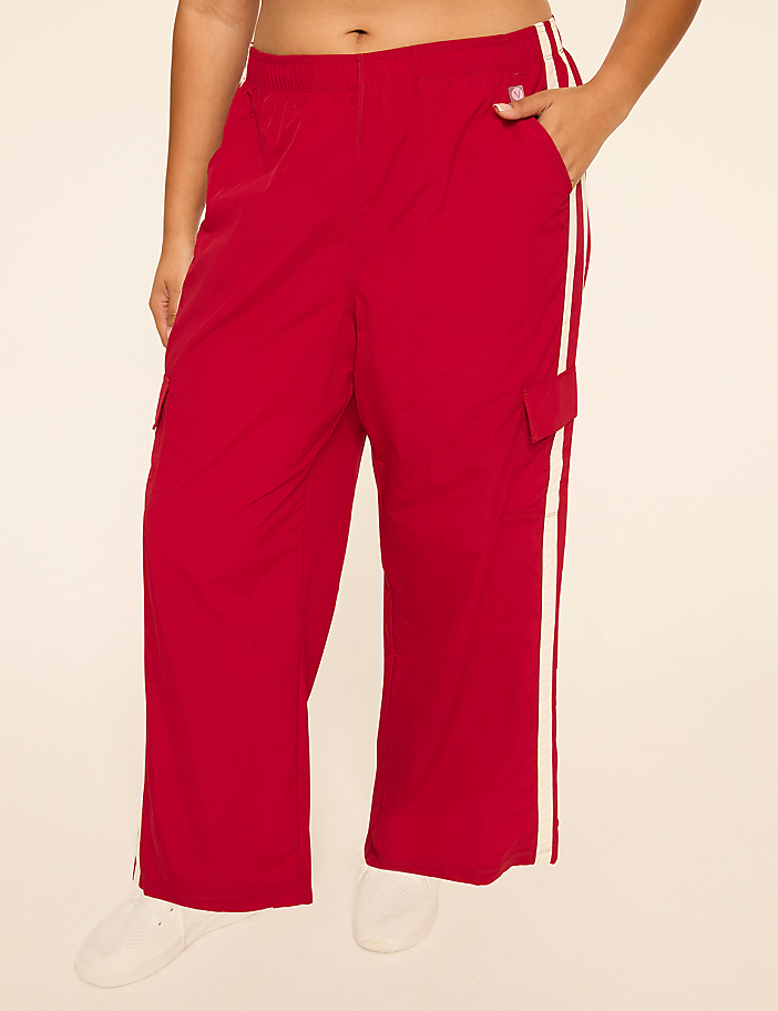 A person stands in red cargo pants with white stripes down the sides, against a plain, light-colored background.