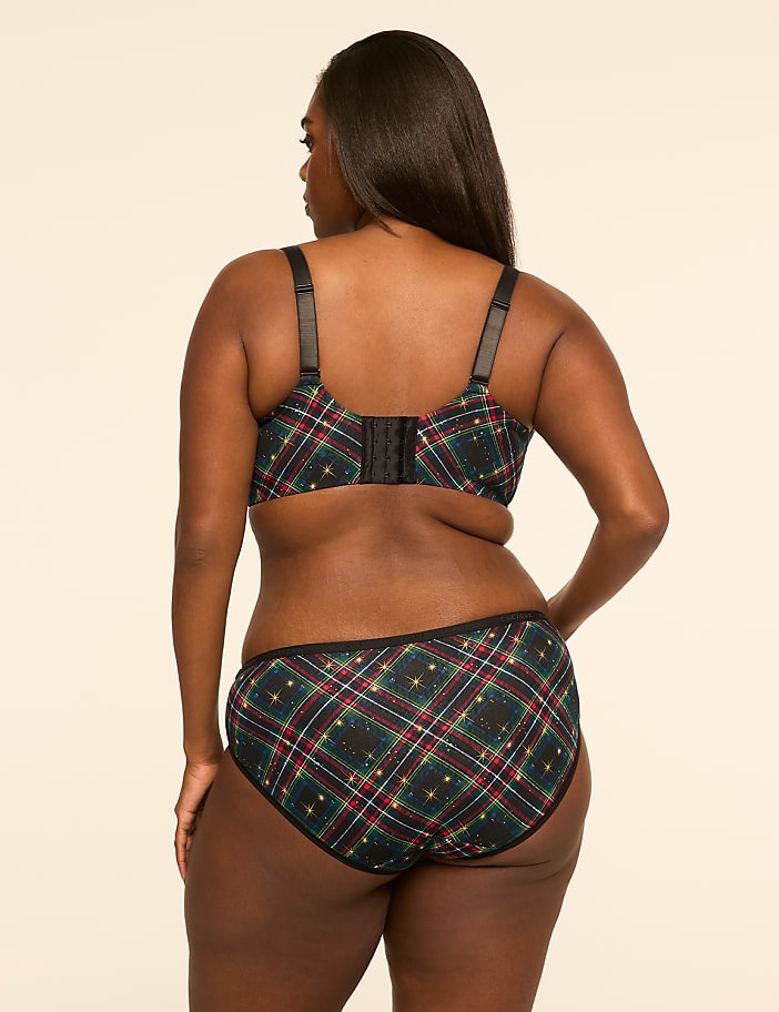 A woman in a plaid bra and underwear stands against a plain, light-colored background.