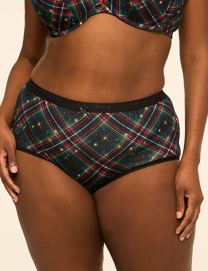 A person models a festive plaid bra and high-waisted briefs against a plain, light-colored background.
