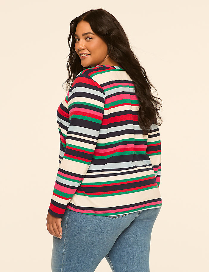 A woman with dark hair and a striped shirt stands against a plain, light-colored background.