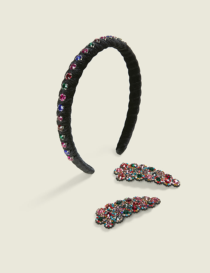 A black velvet headband and two matching jeweled hair clips are arranged on a plain, light-colored background.