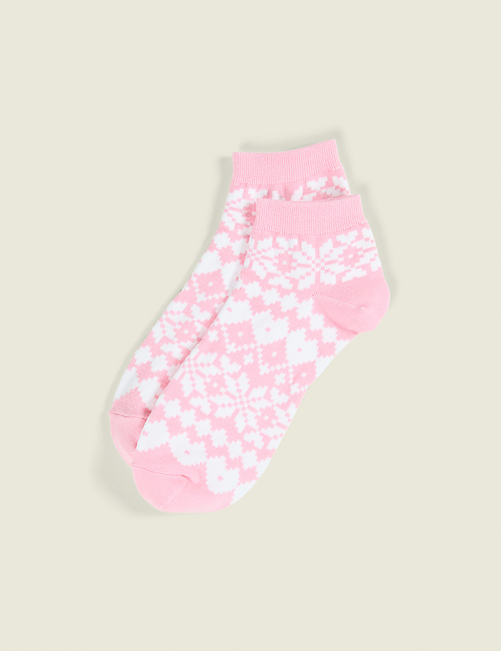 A pair of pink and white patterned socks rests on a plain, light beige background.