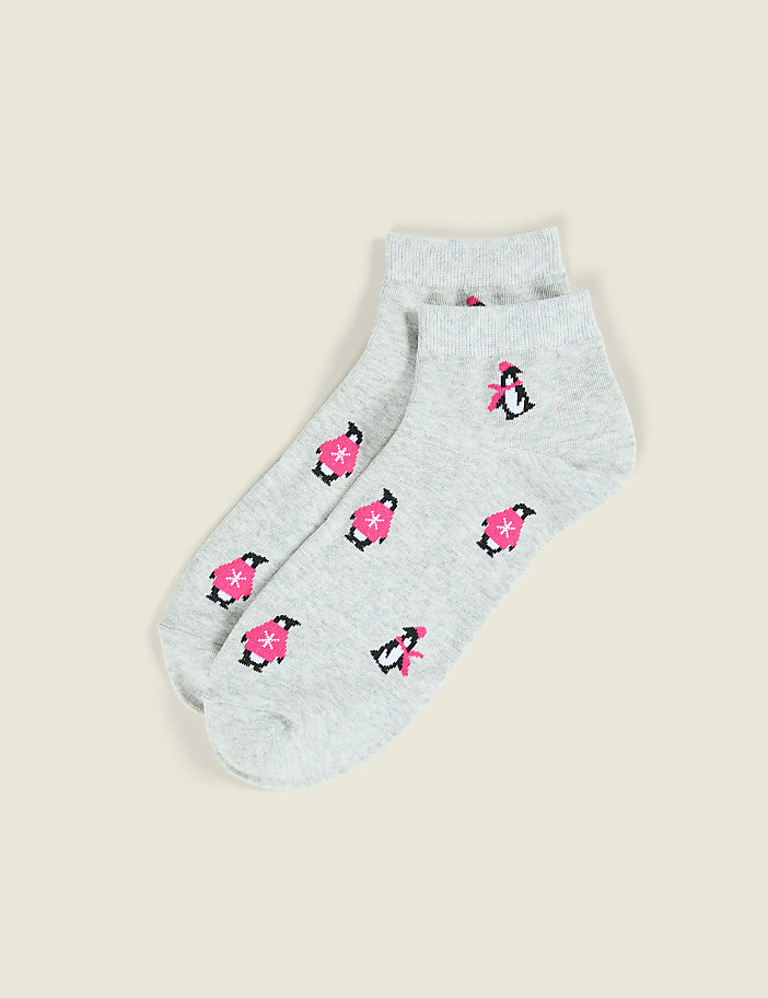 A pair of light grey socks featuring small pink and black penguin patterns rests on a plain beige background.
