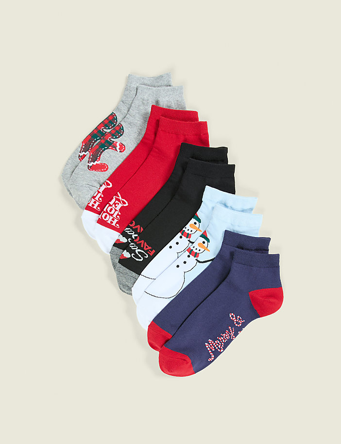 A variety of colorful holiday-themed socks are fanned out against a plain, light beige background.