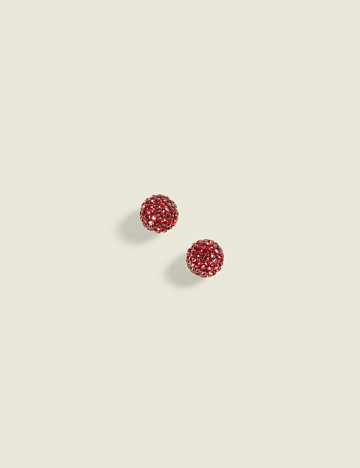 Two sparkling red glittery spheres sit on a plain, light beige background.