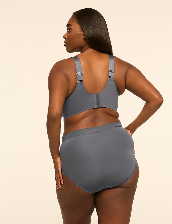 A woman wearing a grey bra and panty set stands with her back to the camera against a plain, light-colored background.