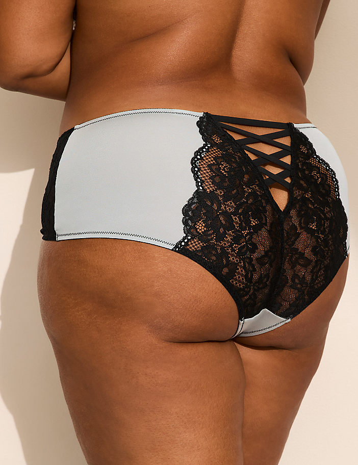 A person wears light blue and black lace panties against a plain, neutral-toned background.