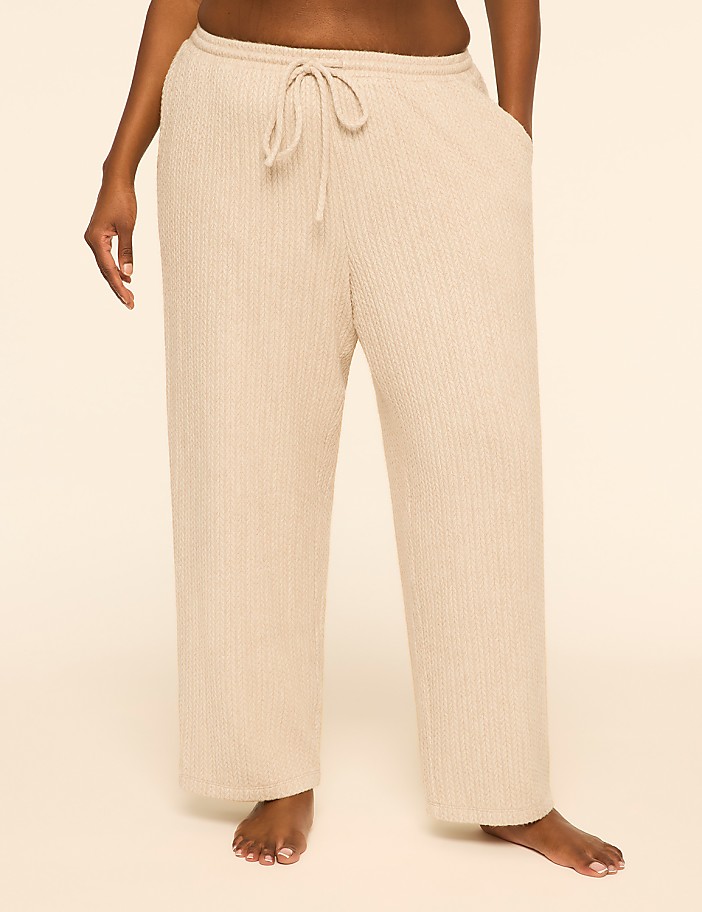 A person wears beige ribbed lounge pants against a plain, light-colored background.