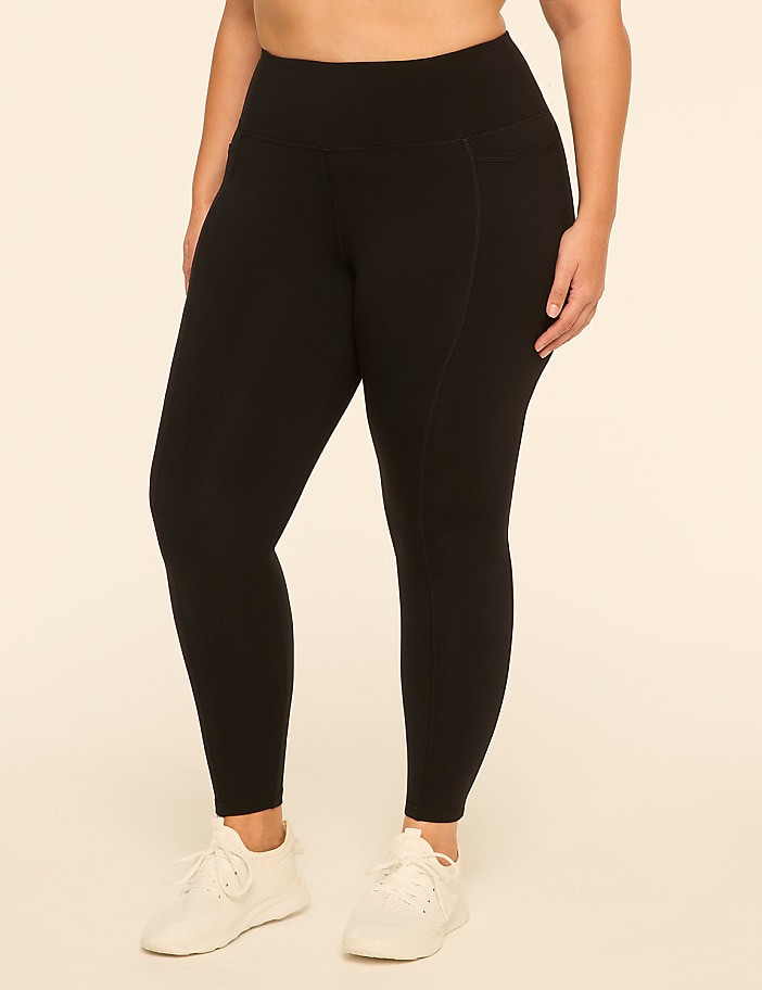 A person wearing black leggings and white sneakers stands against a plain, light-colored background.