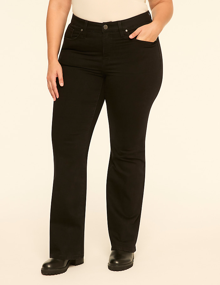 A person wearing a white top, black pants, and black boots stands against a plain, light-colored background.