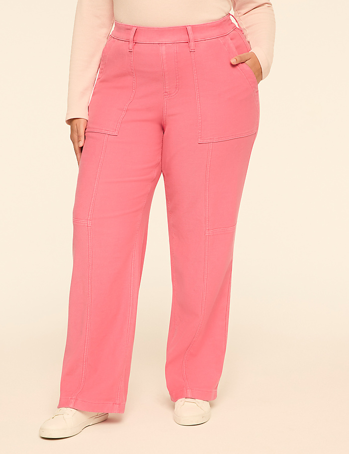 A person wearing bright pink wide-leg pants and white sneakers stands against a plain, light-colored background.