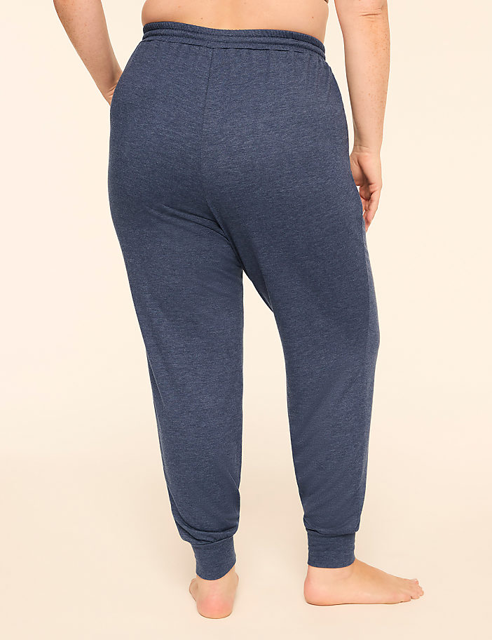 A person wearing navy blue joggers stands against a plain, light-colored background.