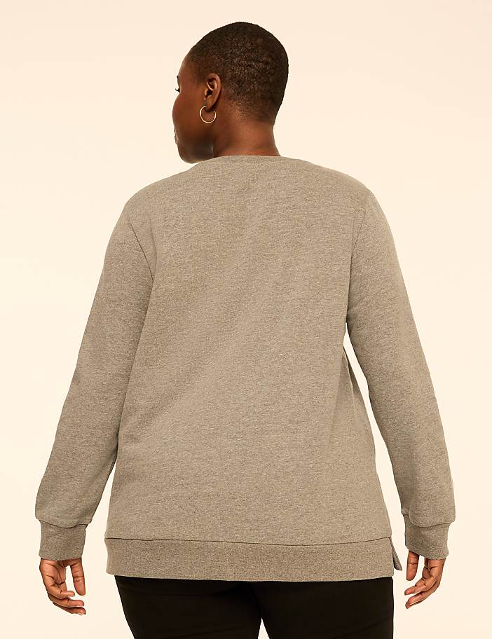 A person wearing a grey long-sleeved sweatshirt and black pants stands with their back to the camera against a plain, light-colored background.