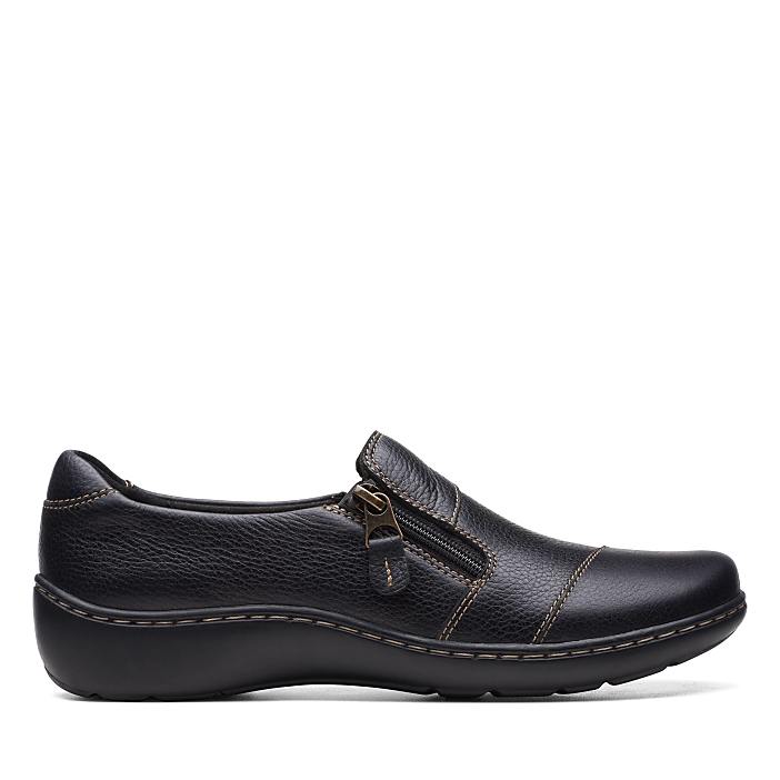 A single black leather shoe with a side zipper sits in the foreground against a plain white background.