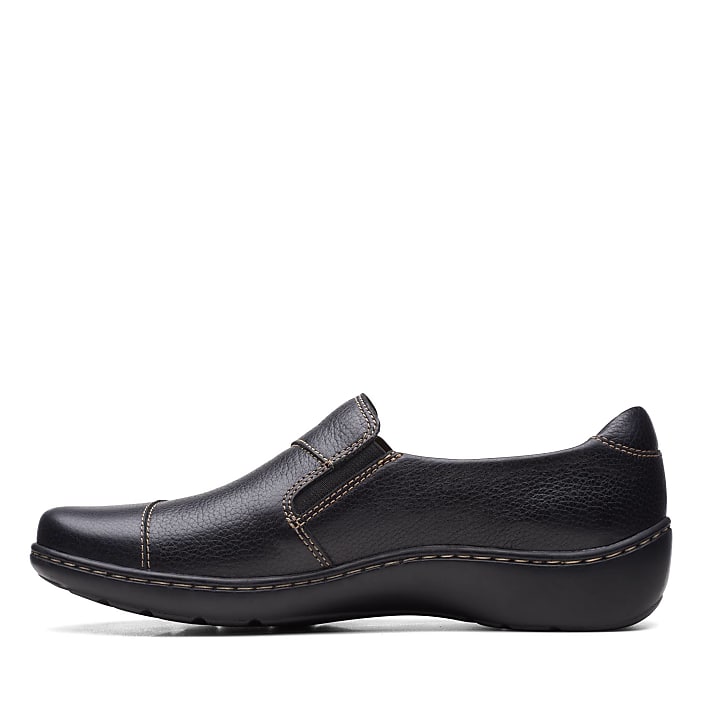 A black leather slip-on shoe sits in the foreground against a plain white background.