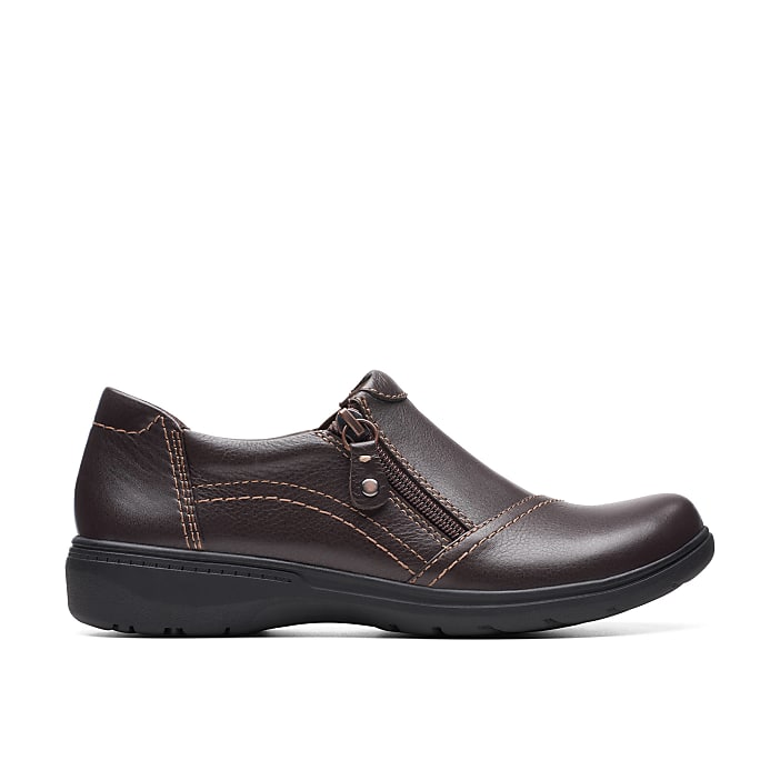 A brown leather shoe with a zipper sits in the foreground against a plain white background.