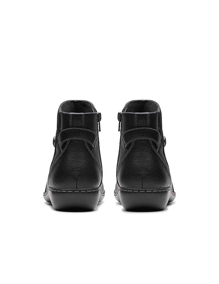 A pair of black leather ankle boots are positioned in the foreground against a plain white background.