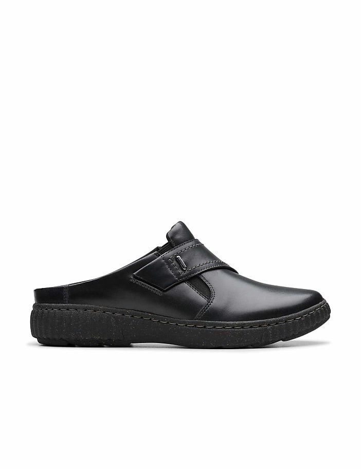 A black leather slip-on shoe sits in the foreground against a plain white background.