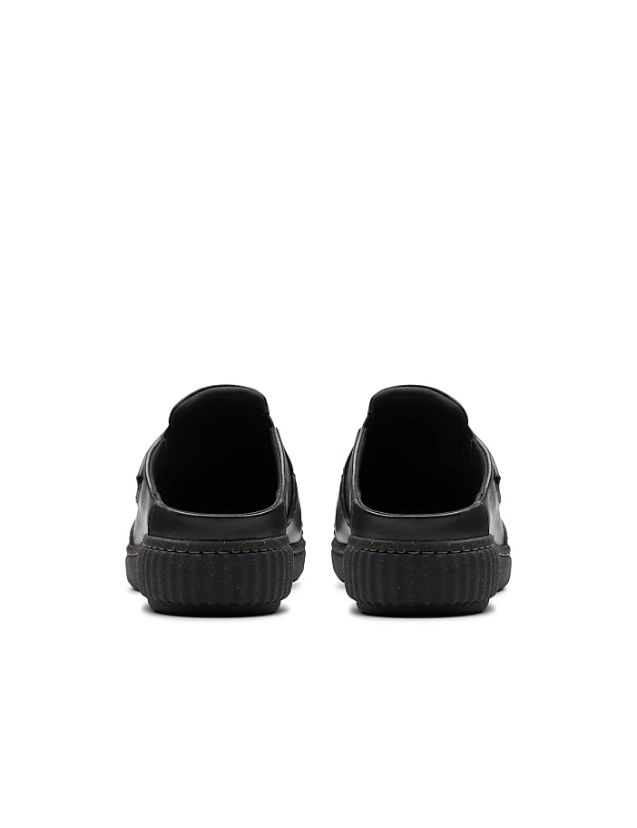 A pair of black slip-on shoes is positioned in the foreground against a plain white background.