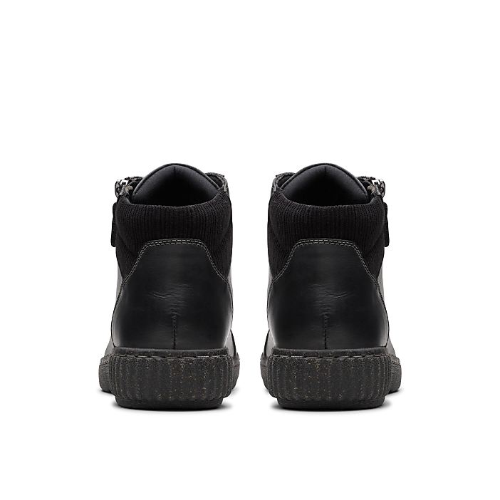 A pair of black leather ankle boots are positioned in the foreground against a plain white background.