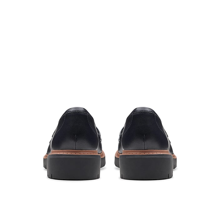 A pair of dark navy leather loafers are positioned in the foreground against a plain white background.
