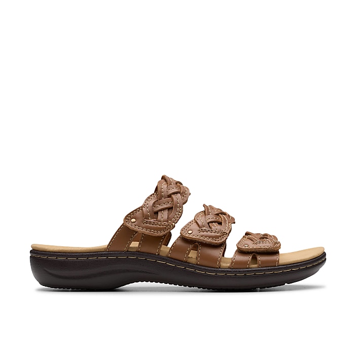 A brown leather braided sandal sits in the foreground against a plain white background.