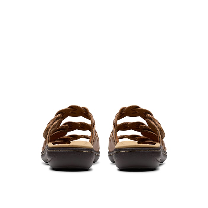 A pair of brown braided sandals sits in the foreground against a plain white background.
