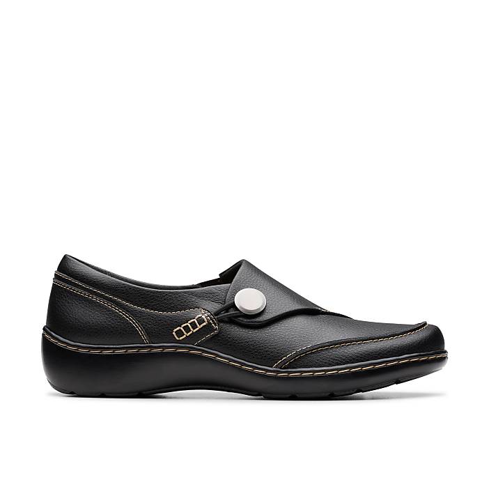 A black leather slip-on shoe with a white button detail sits against a plain white background.