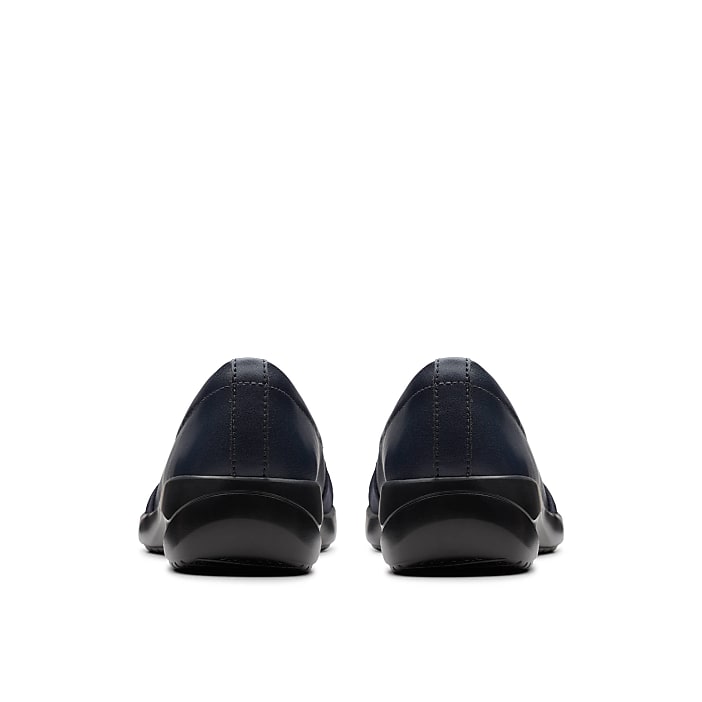 A pair of navy blue slip-on shoes are positioned in the foreground against a plain white background.