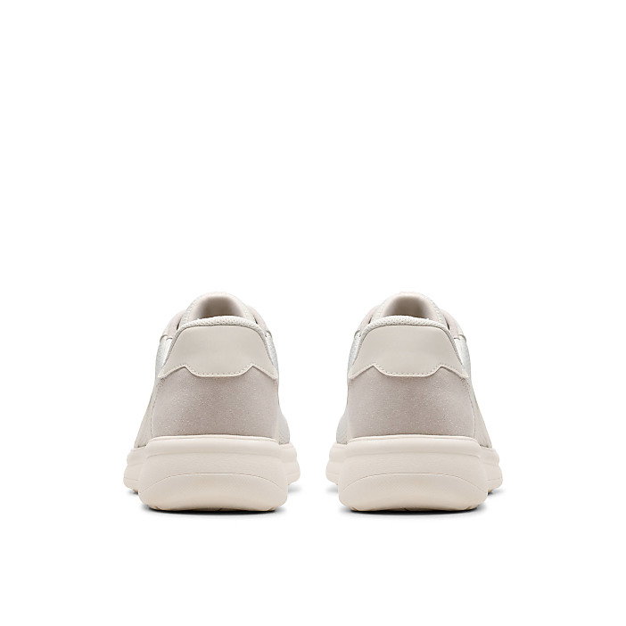 A pair of beige sneakers are positioned side-by-side in the foreground against a plain white background.