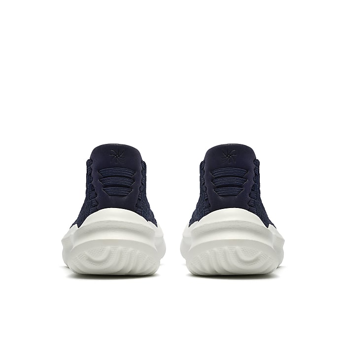 A pair of navy blue sneakers with thick white soles are positioned centrally against a plain white background.