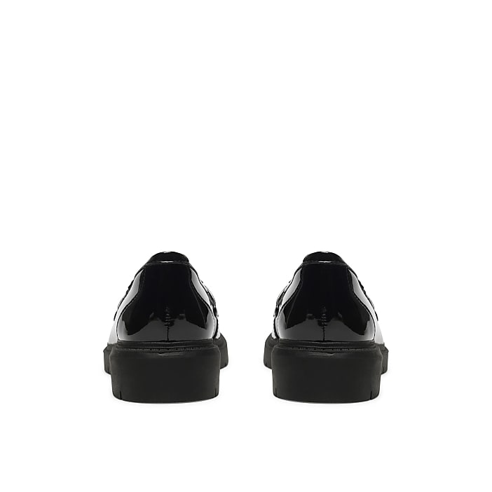 A pair of black patent leather shoes are positioned in the foreground against a plain white background.