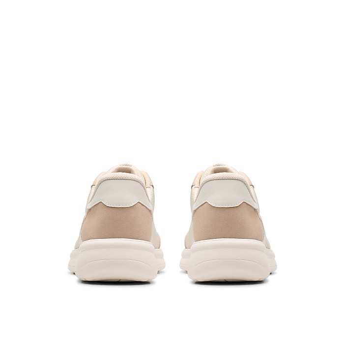 A pair of beige sneakers are positioned in the foreground against a plain white background.
