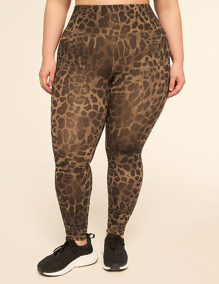 A person wearing leopard-print leggings and black sneakers stands against a plain, light-colored background.