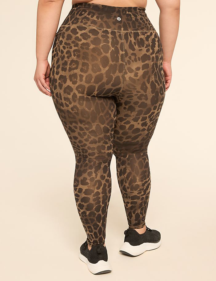 A person wearing leopard print leggings and black sneakers stands against a plain, light-colored background.