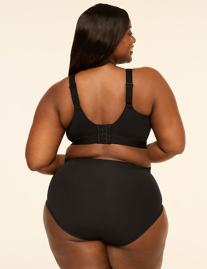 A plus-size woman wearing a black bra and panties stands with her back to the camera against a plain, light-colored background.