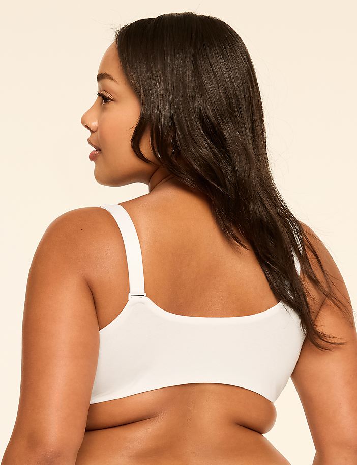 A woman in white lingerie stands with her back to the viewer against a plain, light-colored background.