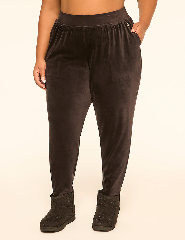 A person wearing brown velvet pants and black Ugg boots stands against a plain cream background.