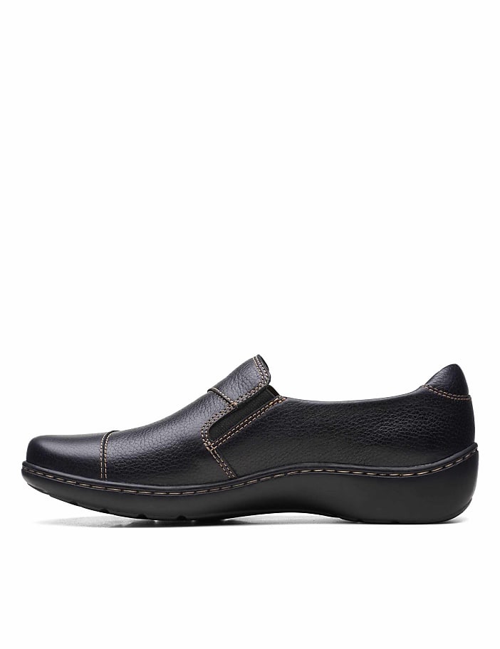 A black leather slip-on shoe sits in the foreground against a plain white background.