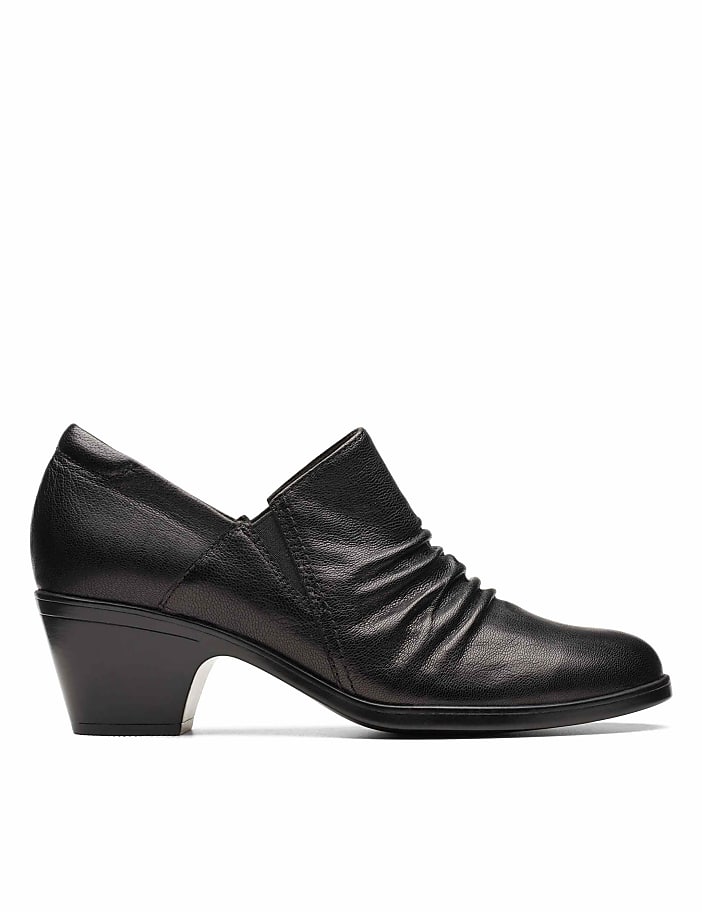 A black leather low-heeled shoe with a ruched front sits against a plain white background.