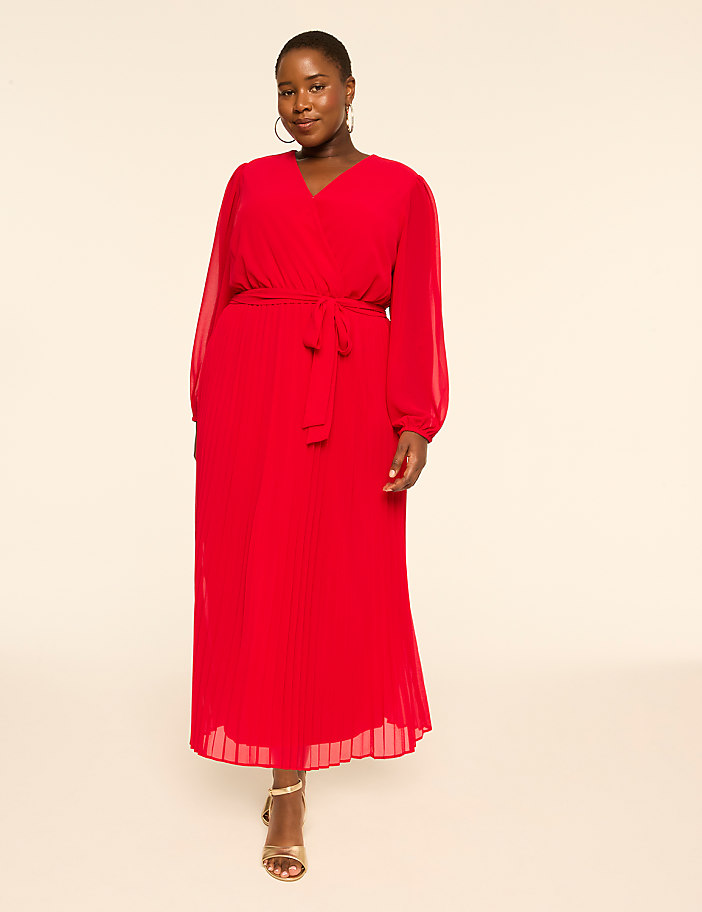 A woman in a red dress stands against a plain, light background.