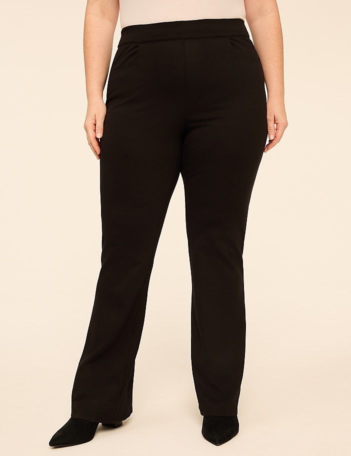 A person wearing black trousers and black shoes stands against a plain, light-colored background.
