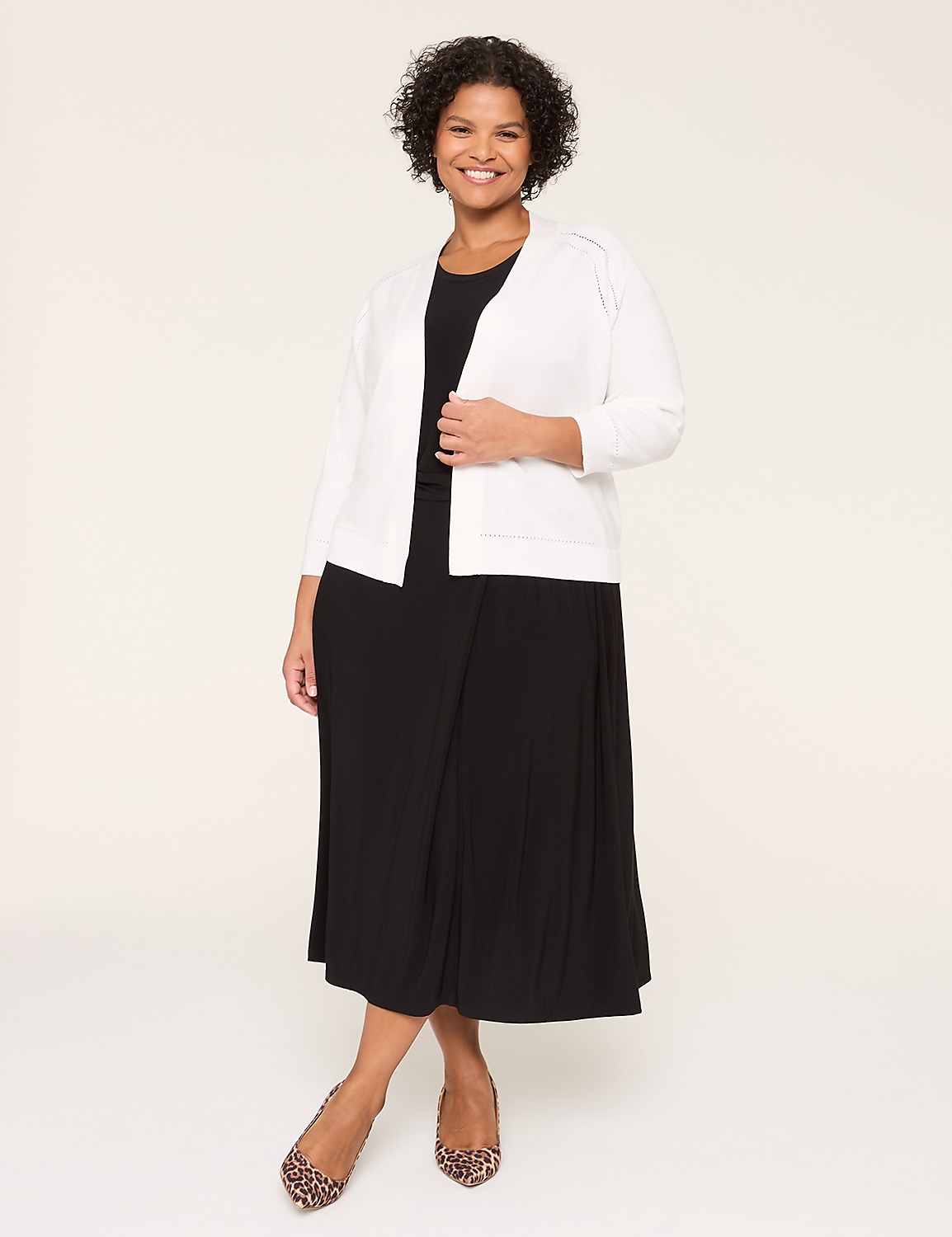 A smiling woman wearing a white jacket and black dress stands against a plain background. Product Image 3