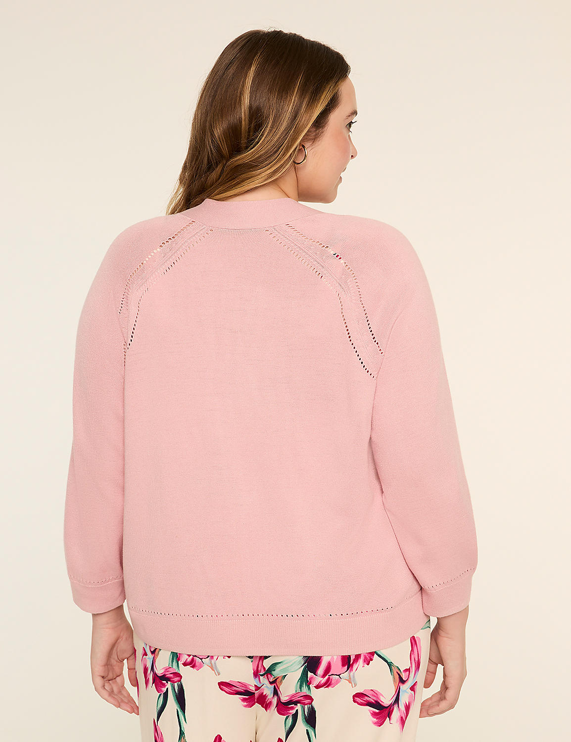 A woman with long, wavy brown hair wearing a pink sweater stands against a plain, light-colored background. Product Image 2