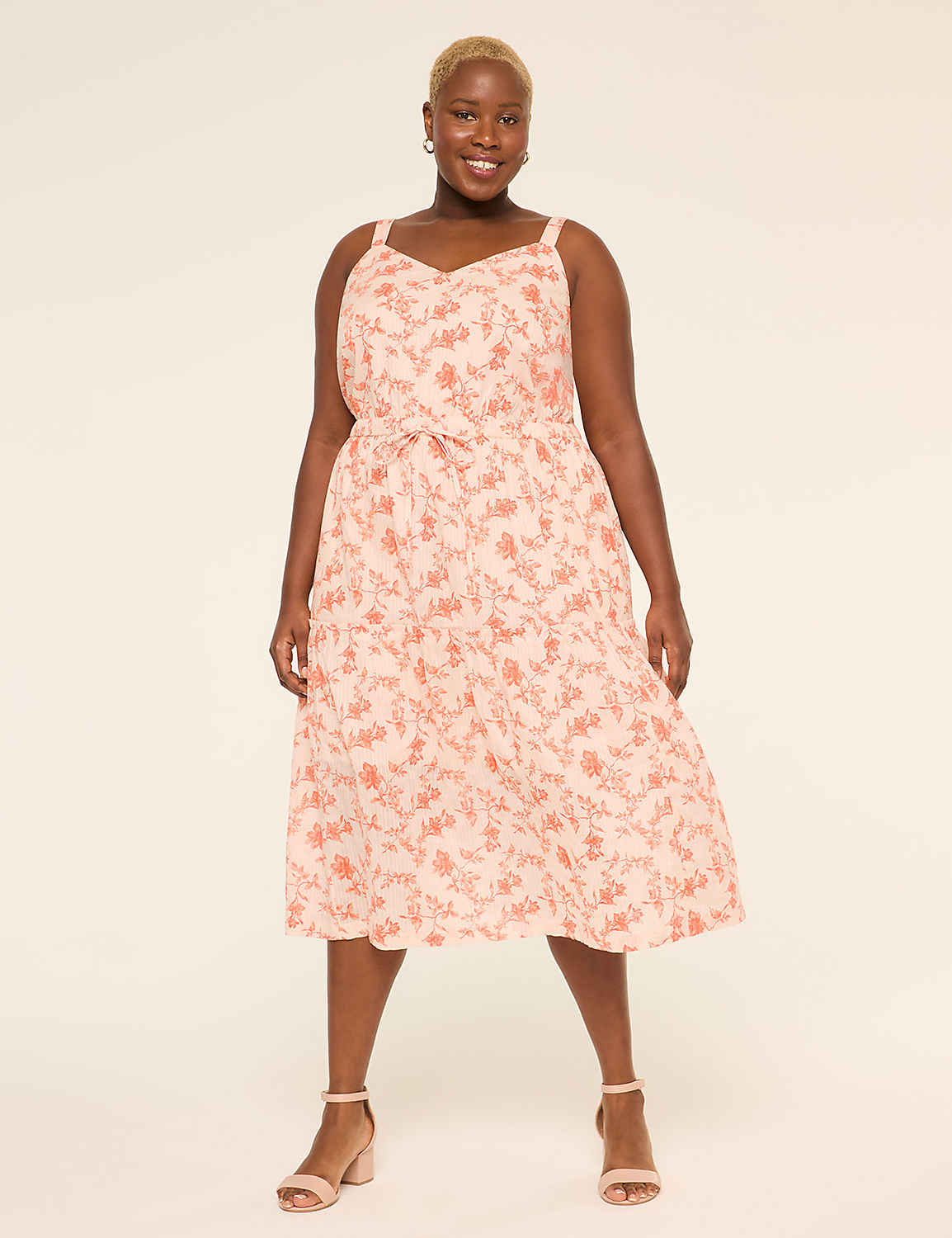 A smiling person wearing a pink floral dress stands against a plain beige background. Product Image 1