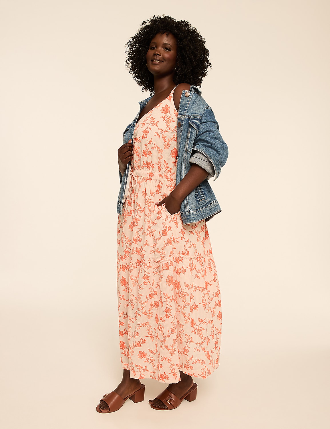 A smiling woman in a floral dress walks along a dirt path surrounded by vegetation, with a body of water visible in the background. Product Image 4