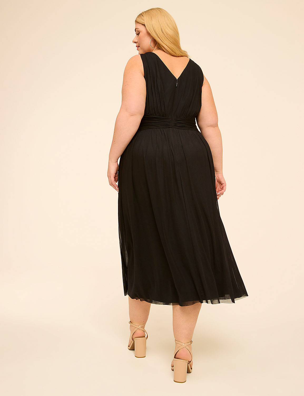 A woman in a black V-neck dress walks away from the camera against a plain, light-colored background. Product Image 2